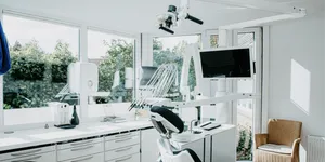 Helles Behandlungszimmer mit Behandlungsstuhl und Mikroskop